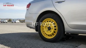  A silver car parked on a highway shoulder with a yellow compact temporary spare tire installed. - How far can you drive on a spare tire