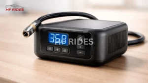 A compact black air compressor sits on a wooden table, displaying "36.8" on its digital screen. Buttons below and hose attached convey functionality. - How to Fill Car Tires with Air at a Gas Station